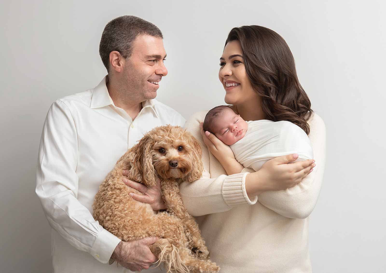 family portrait with newborn and golden doodle captured in the comfort of home