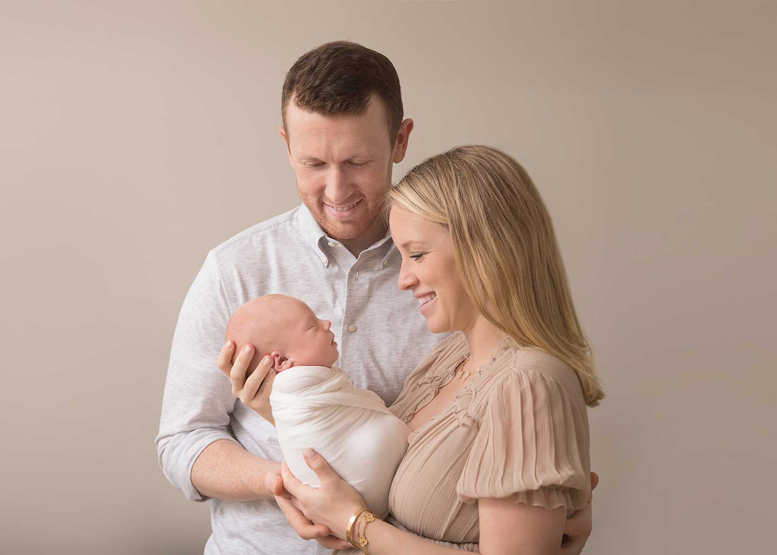 family cuddling newborn for in home baby photoshoot