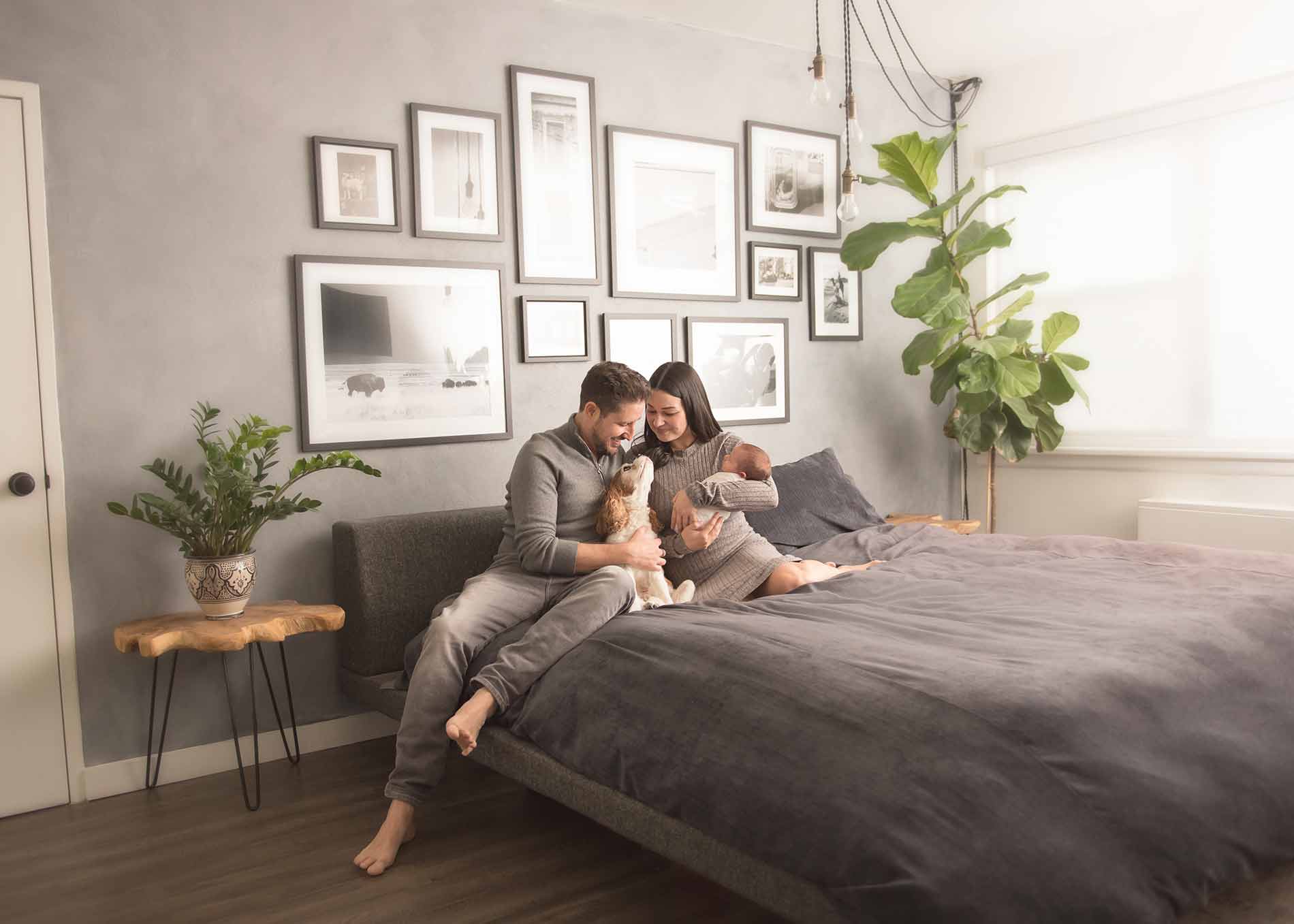 Photo of a modern Denver family sitting on bed with their newborn baby